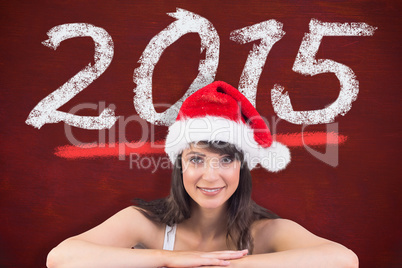 Composite image of festive brunette leaning on large poster