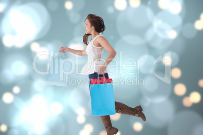 Composite image of happy brunette leaping with shopping bags