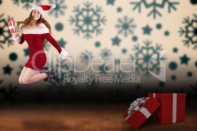 Composite image of festive redhead jumping with gift