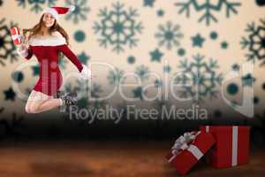 Composite image of festive redhead jumping with gift