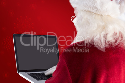 Composite image of santa claus uses a laptop