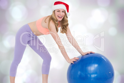 Composite image of festive blonde woman using exercise ball