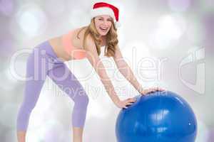Composite image of festive blonde woman using exercise ball