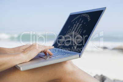 Composite image of woman sitting on beach using her laptop