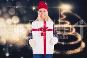 Composite image of festive blonde holding a gift