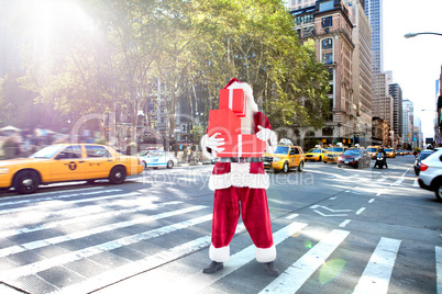 Composite image of santa covers his face with presents