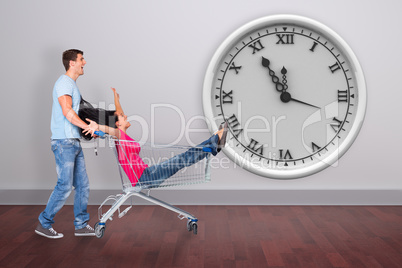 Composite image of young couple having fun with shopping cart