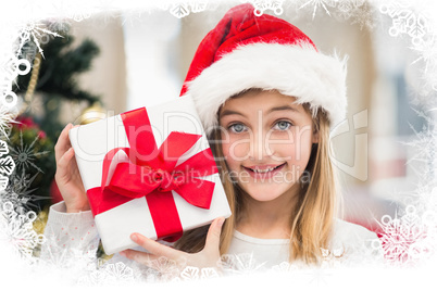 Composite image of festive little girl holding a gift