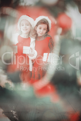 Composite image of festive little girls smiling at camera with g