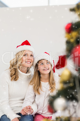 Composite image of festive mother and daughter smiling at tree