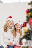 Composite image of festive mother and daughter smiling at tree