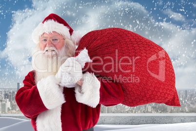 Composite image of santa carries his red bag and smiles