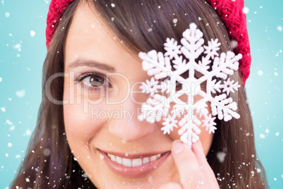 Composite image of festive brunette holding snowflake decoration