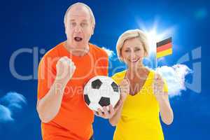 Composite image of happy german couple cheering at camera holdin