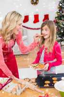 Composite image of festive mother and daughter making christmas cookies