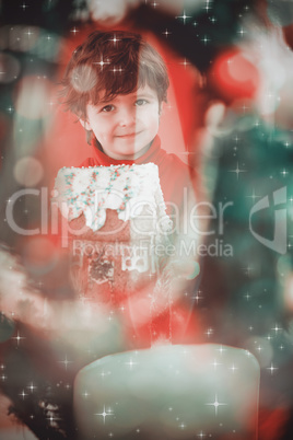 Composite image of festive little boy holding gingerbread house