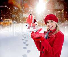 Composite image of festive blonde holding red gift