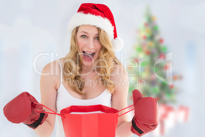 Composite image of shocked blonde opening a shopping bag with bo