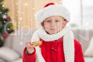 Composite image of festive little boy eating a cookie