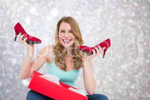 Composite image of smiling woman holding up her new shoes
