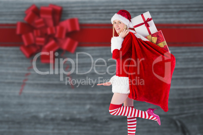Composite image of festive blonde carrying sack of presents