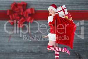 Composite image of festive blonde carrying sack of presents