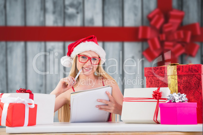 Composite image of festive blonde writing her christmas list