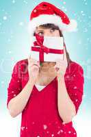 Composite image of festive young woman holding a gift