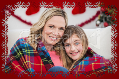 Composite image of festive mother and daughter wrapped in blanke