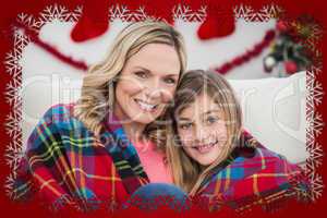 Composite image of festive mother and daughter wrapped in blanke