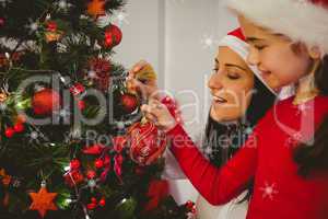 Composite image of mother and daughter hanging christmas decorat