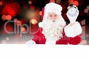 Composite image of santa claus holding alarm clock and sign