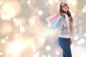 Composite image of brunette with glasses holding shopping bags