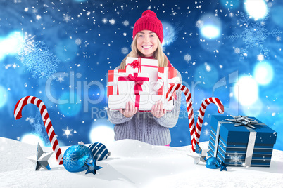 Composite image of festive blonde holding pile of gifts