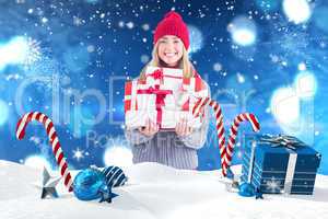 Composite image of festive blonde holding pile of gifts