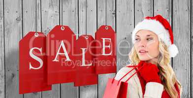 Composite image of happy festive blonde with shopping bag