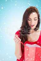 Composite image of brunette in red dress looking in shopping bag