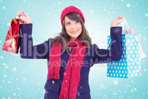 Composite image of pretty brunette holding up shopping bags