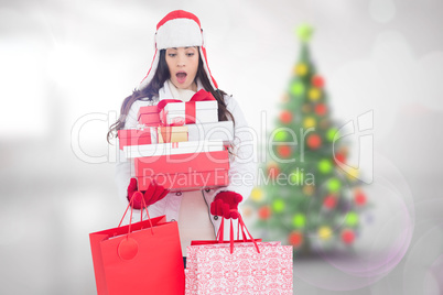 Composite image of surprised brunette in winter clothes holding