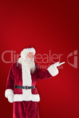 Composite image of santa shows something to camera