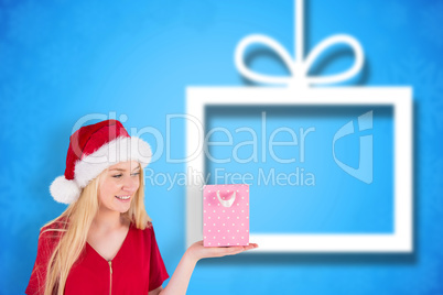 Composite image of festive blonde holding a gift bag