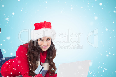 Composite image of festive brunette shopping online with laptop