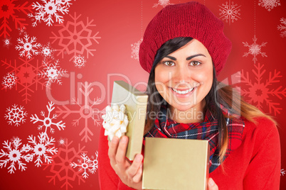 Composite image of smiling brunette opening christmas gift