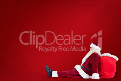 Composite image of santa sits leaned on his bag