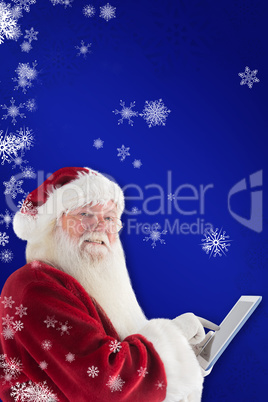 Composite image of santa uses a tablet pc and smiles into the ca