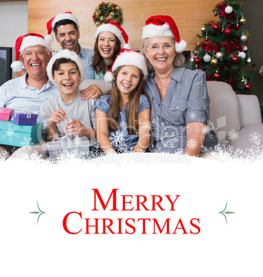 Composite image of extended family in christmas hats with gift b