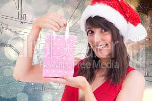 Composite image of festive brunette holding a gift bag
