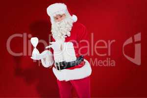 Composite image of smiling santa claus holding hourglass