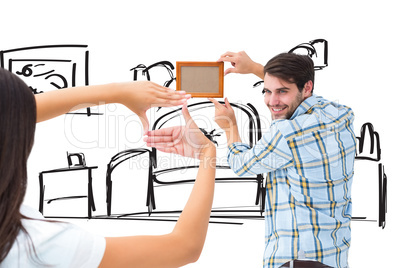 Composite image of happy young couple putting up picture frame