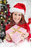 Composite image of festive redhead holding christmas gift